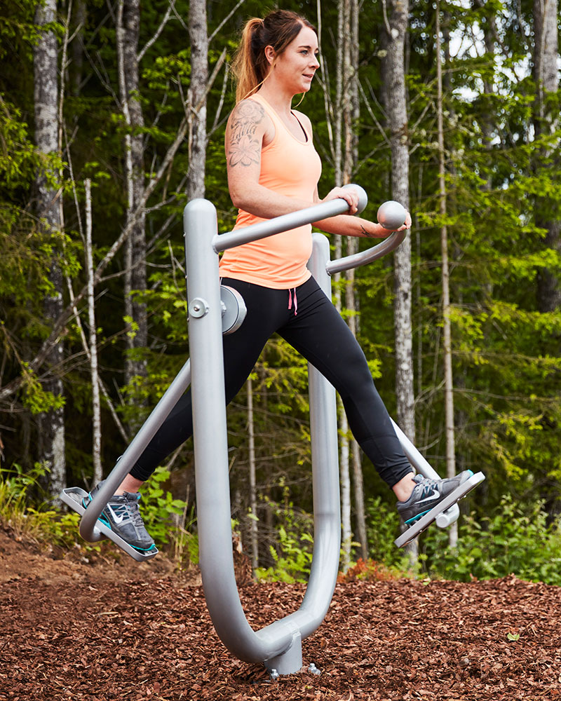 A woman works out among nature at an outdoor gym park. | HAGS